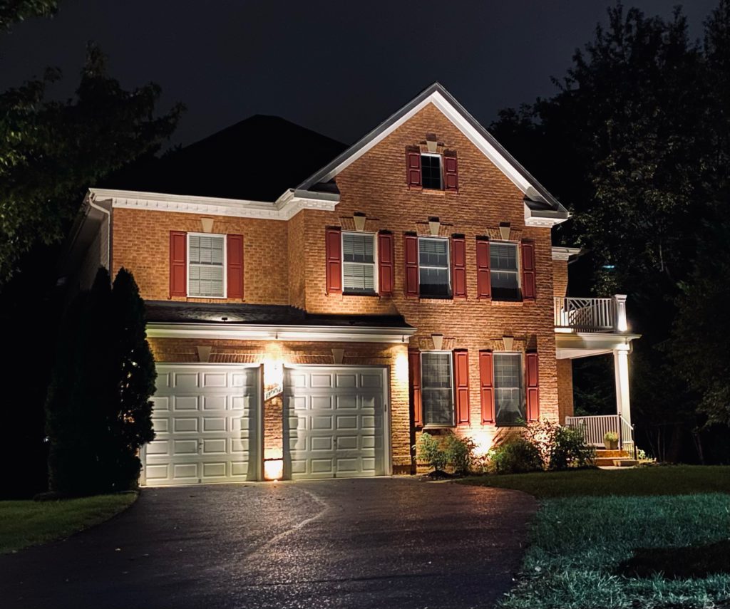 Illuminated two-garage house at night showing outdoor lighting